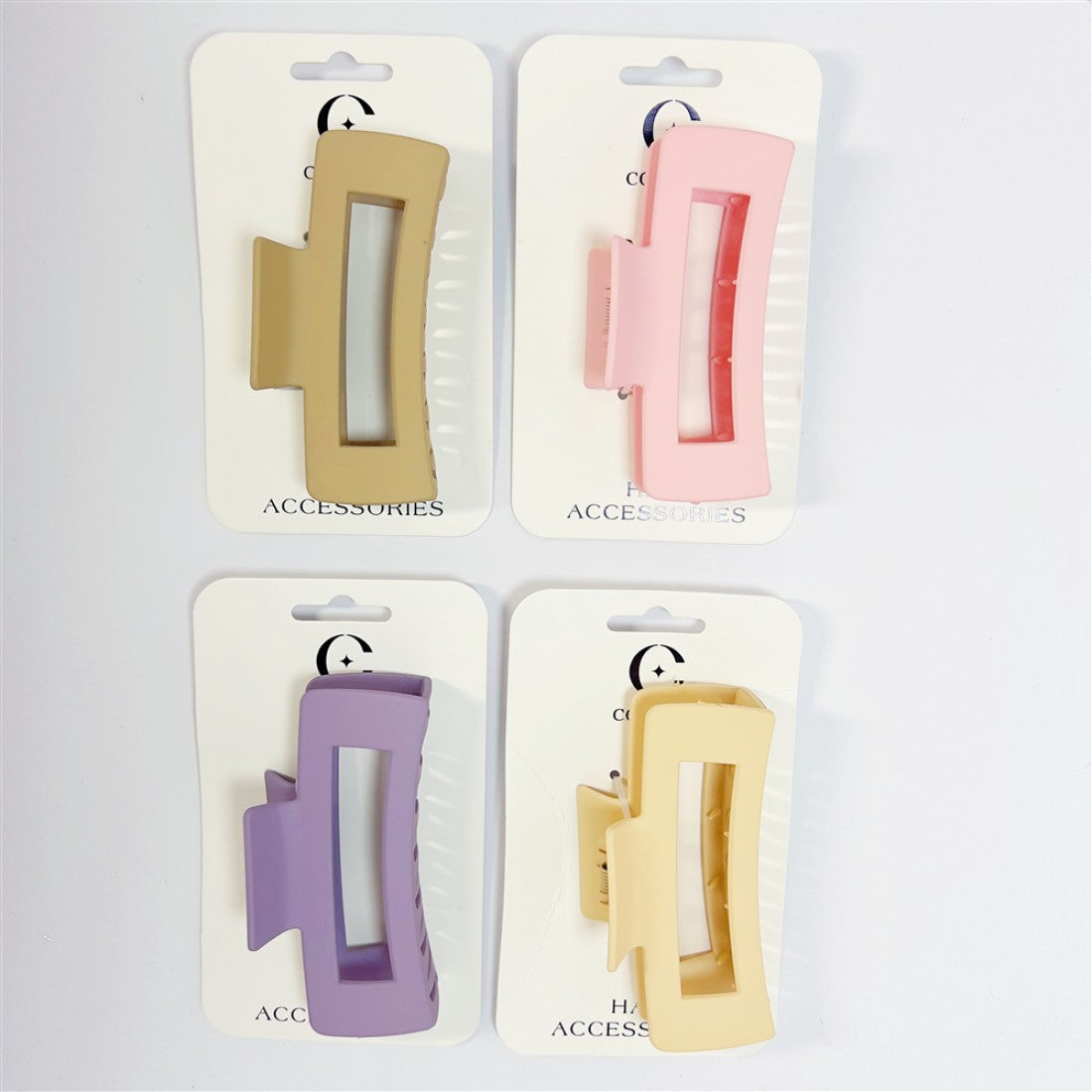 Large rectangular hair claw clips with cut-out centre; Matte plastic finish; Soft pastel colours including beige, pink, purple and yellow; Mounted on white branded hair accessories cards;