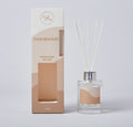 clear glass bottle with silver cap; white reed sticks; sandy beige and cream coloured packaging; label and box feature minimalist text and logo;