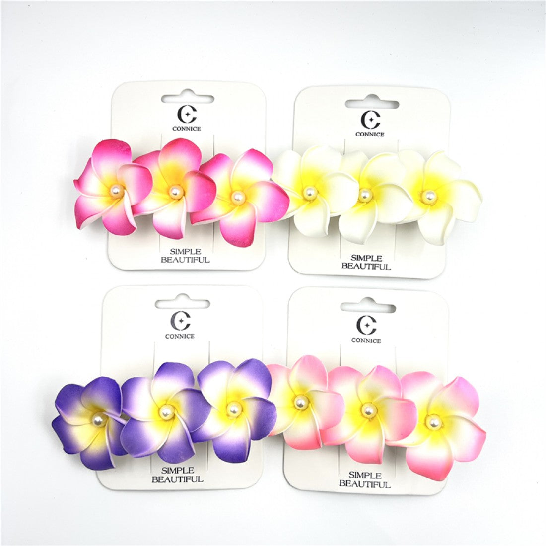 Foam frangipani flowers with gradient colouring; Flowers feature a small pearl bead at the centre; Mounted on white branded backing cards; Assorted colours including pink, yellow-white and purple tones;