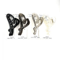 Heart-shaped claw clip design; Approx. 13cm long hair clip; Neutral colours including black, brown, grey and clear; Mounted on branded backing card; Curved, open-frame plastic construction;