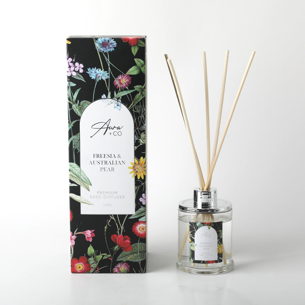 clear glass bottle with chrome cap; natural reed sticks; black floral patterned packaging; white label with product name; liquid diffuser solution;