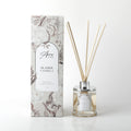 Clear glass bottle with silver collar; Light beige liquid inside the bottle; Thin natural reed sticks included; Decorative box with floral and seashell pattern in neutral tones;