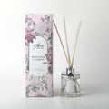 clear glass bottle; silver metal cap; natural reed sticks; pink floral designed box; liquid fill visible;
