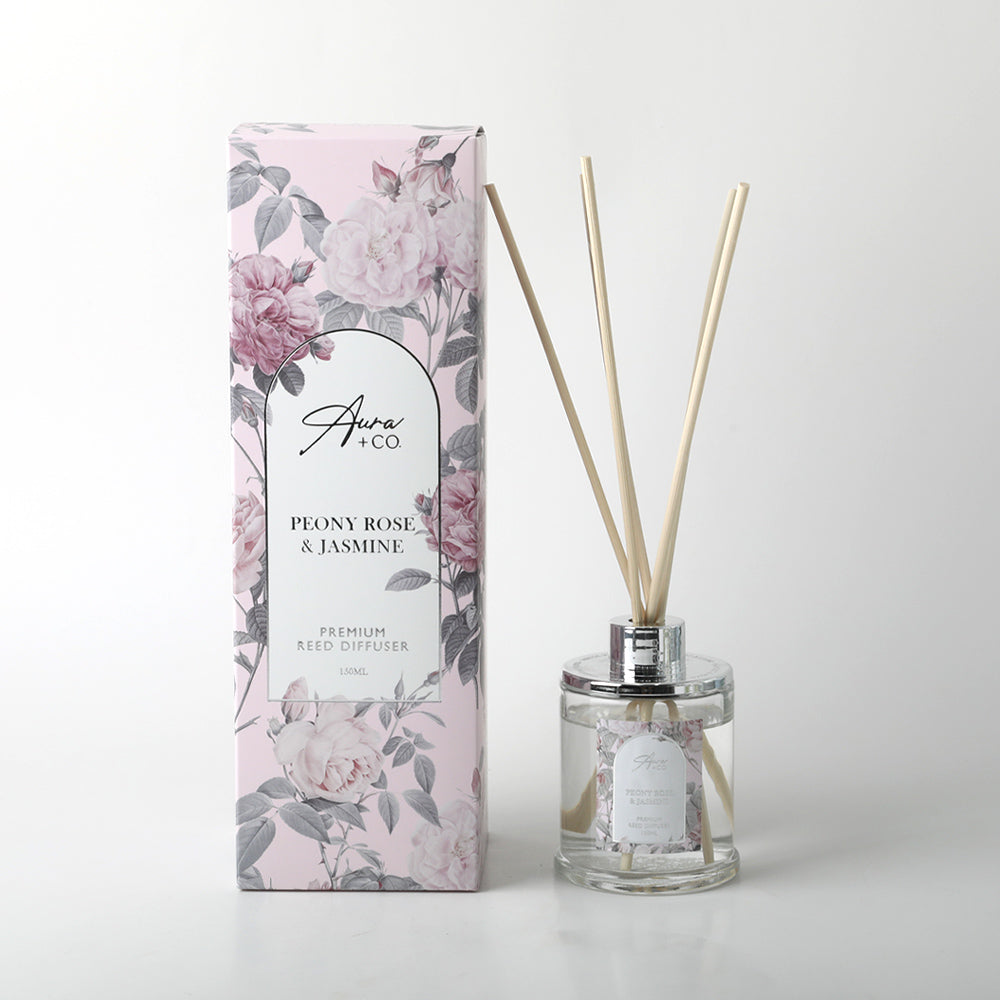 clear glass bottle; silver metal cap; natural reed sticks; pink floral designed box; liquid fill visible;