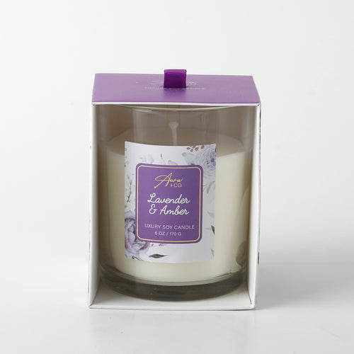white candle in clear glass jar; purple label with floral design; purple box with pull tab; wax appears smooth and creamy;