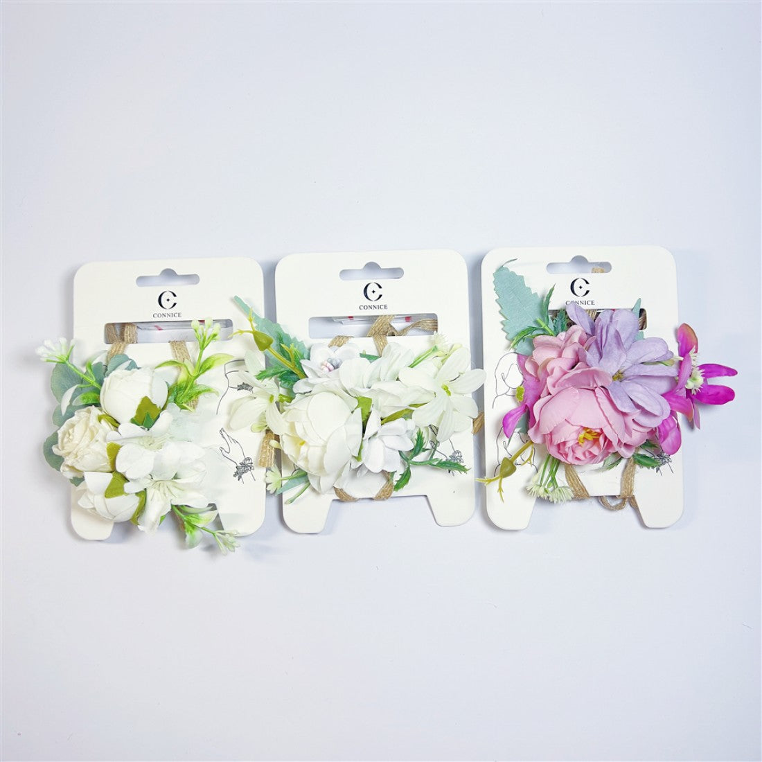Artificial flower clusters mounted on white branded backing cards; Mixed colours including white, cream, pink and purple blooms; Green foliage and leaves surrounding the flowers; Natural twine-style ties securing the flower clusters;