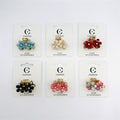 Small flower-shaped hair claw clip; Gold-tone alloy claw base; Petal-style flowers with central rhinestone detail; Mounted on branded backing card labelled "Connice" and "Hair Accessories"; Shown in several assorted colours including blue, cream, red, black, pink and multicolour;