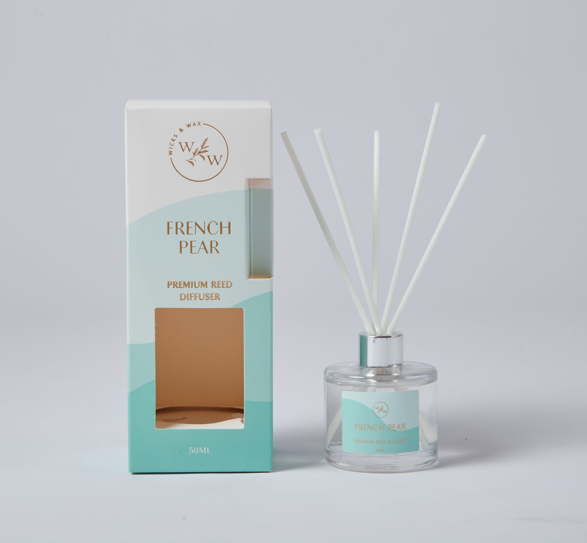 Clear glass container with silver collar; Five white reeds; Blue and white packaging with gold text; Rectangular box with cutout window; Label matching the box design;