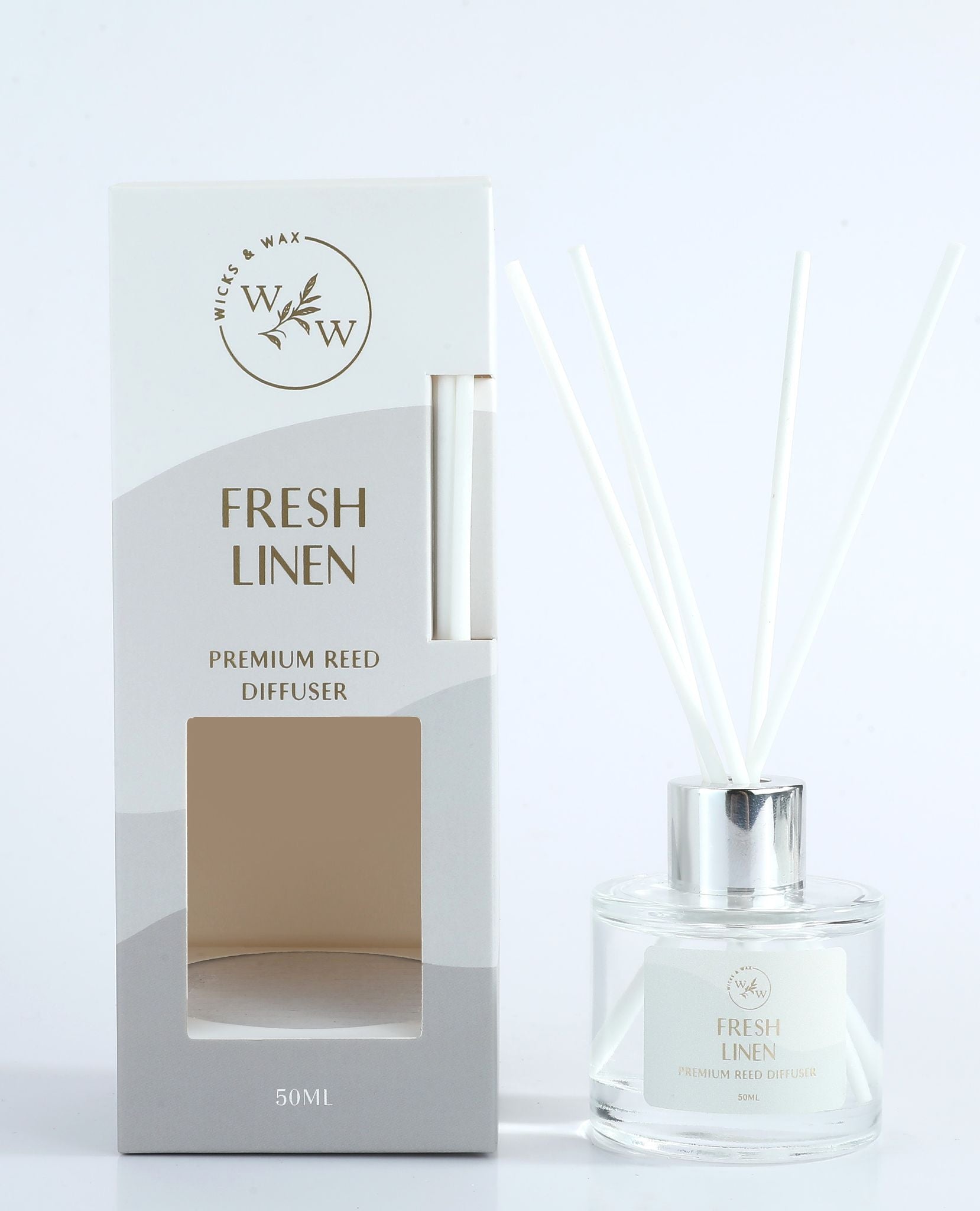Clear round glass bottle; Silver-coloured cap; White reed sticks; Light grey and white packaging with cut-out window; Label and box text show 'Fresh Linen' scent;