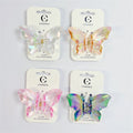 Butterfly-shaped plastic hair claw clips; Iridescent, pearly UV-like finish; Pastel colours including white, orange, pink and green-purple; Mounted on white backing cards branded "Connice"; Metal spring hinge at centre of clip;