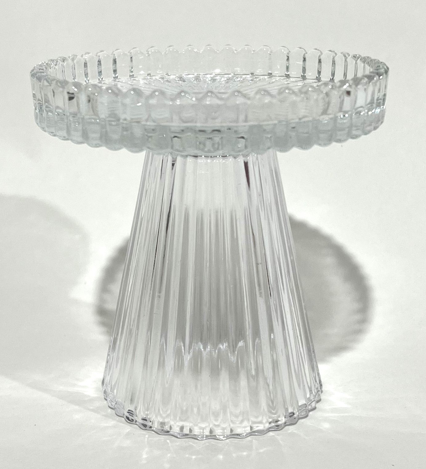 Clear transparent ribbed glass material; Short pedestal style candle holder; Circular top with ridged edge; Compact size approximately 9.8x9.7cm;
