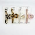 Long cross-shaped hair claw clip; Colours including tortoiseshell, cream and pink; Acrylic, glossy finish; Gold-toned claw teeth and spring mechanism; Packaged on white branded backing card;