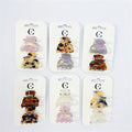 Small half moon shaped claw clips; Assorted marbled and iridescent colours; Acrylic material with metal spring mechanism; Clips presented on white branded backing cards;