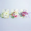 Artificial flower cluster design with layered petals; Available in light, pastel and multicolour arrangements; Includes green leaf accents and small buds; Mounted on white backing card branded “Connice”; Ribbon detail in matching pastel shade on each clip;