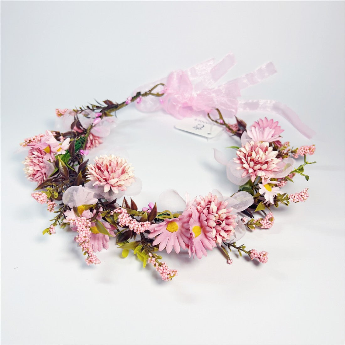 Circular wreath decorated with pink artificial flowers; Mix of daisy-style and chrysanthemum-style blooms; Green leaves and small pink berry-like clusters; Sheer pink ribbon bow and ties at the back; Brown vine-style base structure;