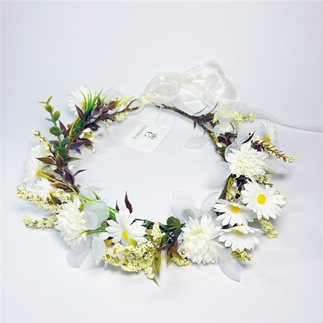 Circular wreath shape with flexible vine base; White daisy-style and chrysanthemum-style flowers; Green and brown foliage with small cream filler flowers; Sheer white ribbon bow and tie at the back; Product tag attached to the wreath;