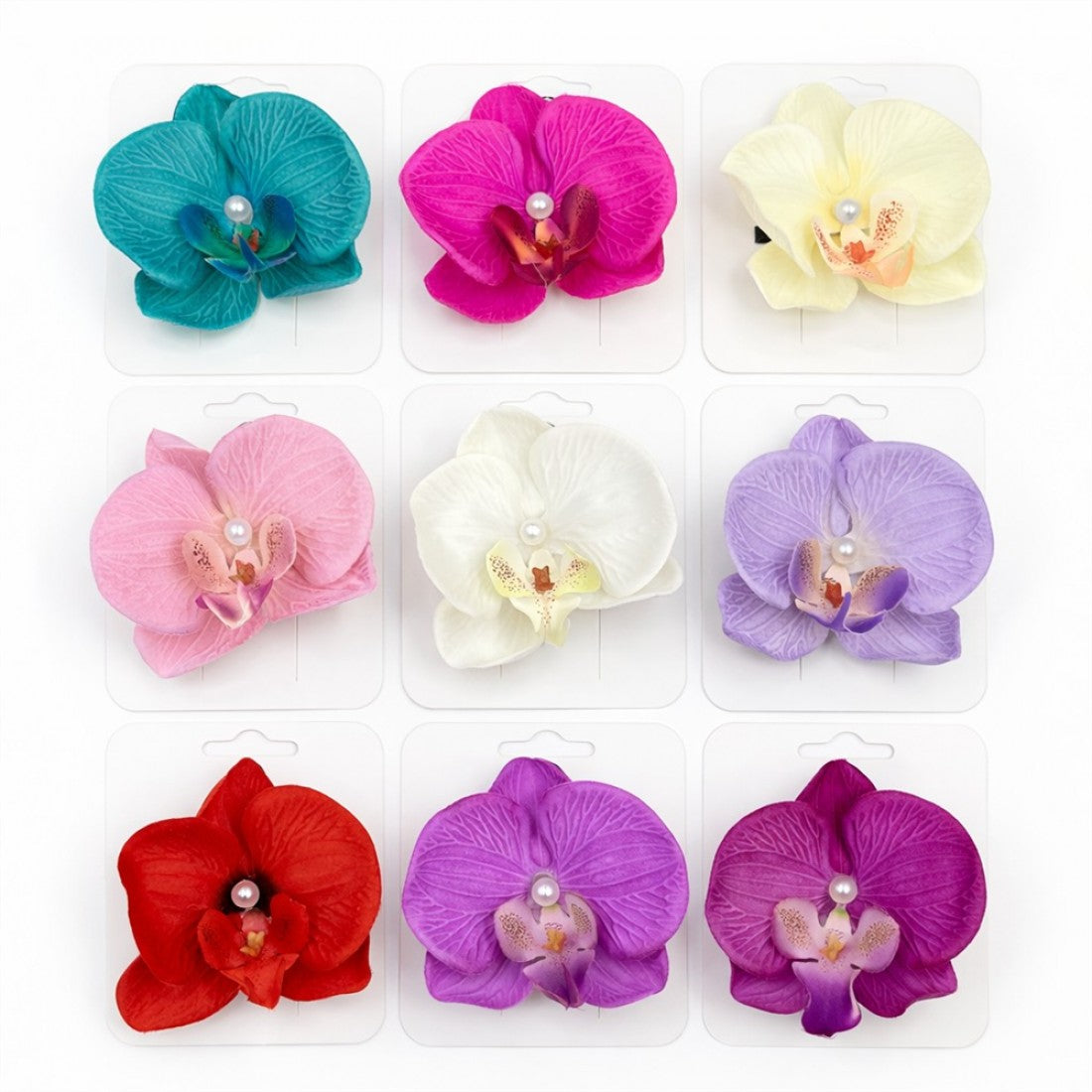 Large orchid-shaped hair clips with textured petals; Range of colours including teal, pink, cream, red and purple tones; Each clip features a small faux pearl at the centre; Mounted on individual white hanging display cards;