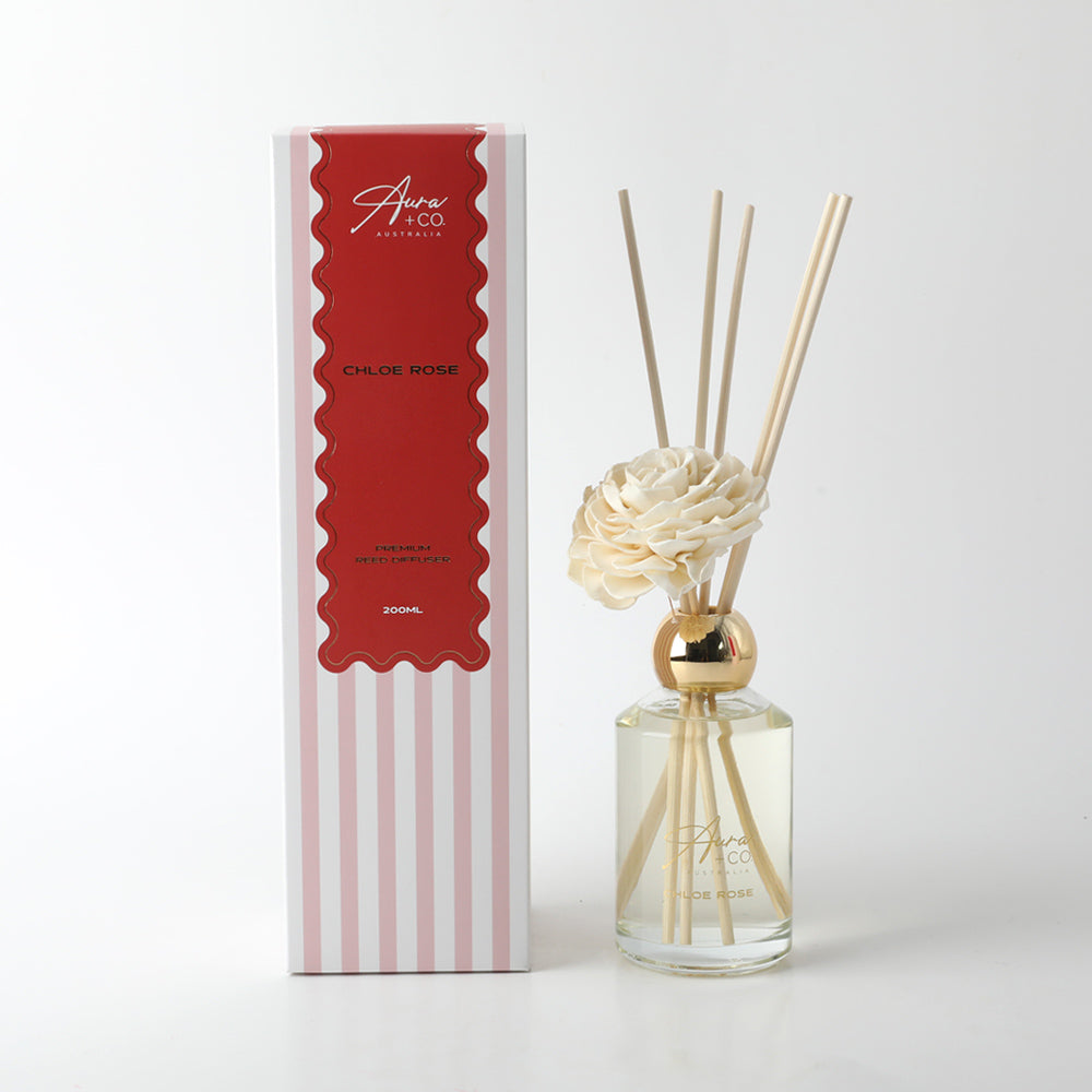 Clear glass bottle; Light yellow diffuser liquid; Natural wood reeds; White foam flower decoration; Striped and red accented packaging box;
