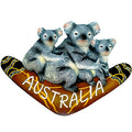 three koalas sitting on a brown boomerang; boomerang features painted Aboriginal-style designs; word 'AUSTRALIA' painted in white on boomerang; magnet likely comes in a single piece; resin material with detailed texture and colour;