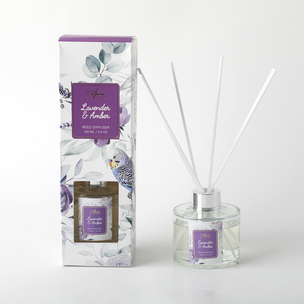 Clear glass bottle with silver collar; White reed diffuser sticks; Box with floral and native bird print in purple tones; Purple label with product name; 100ml volume indicated;