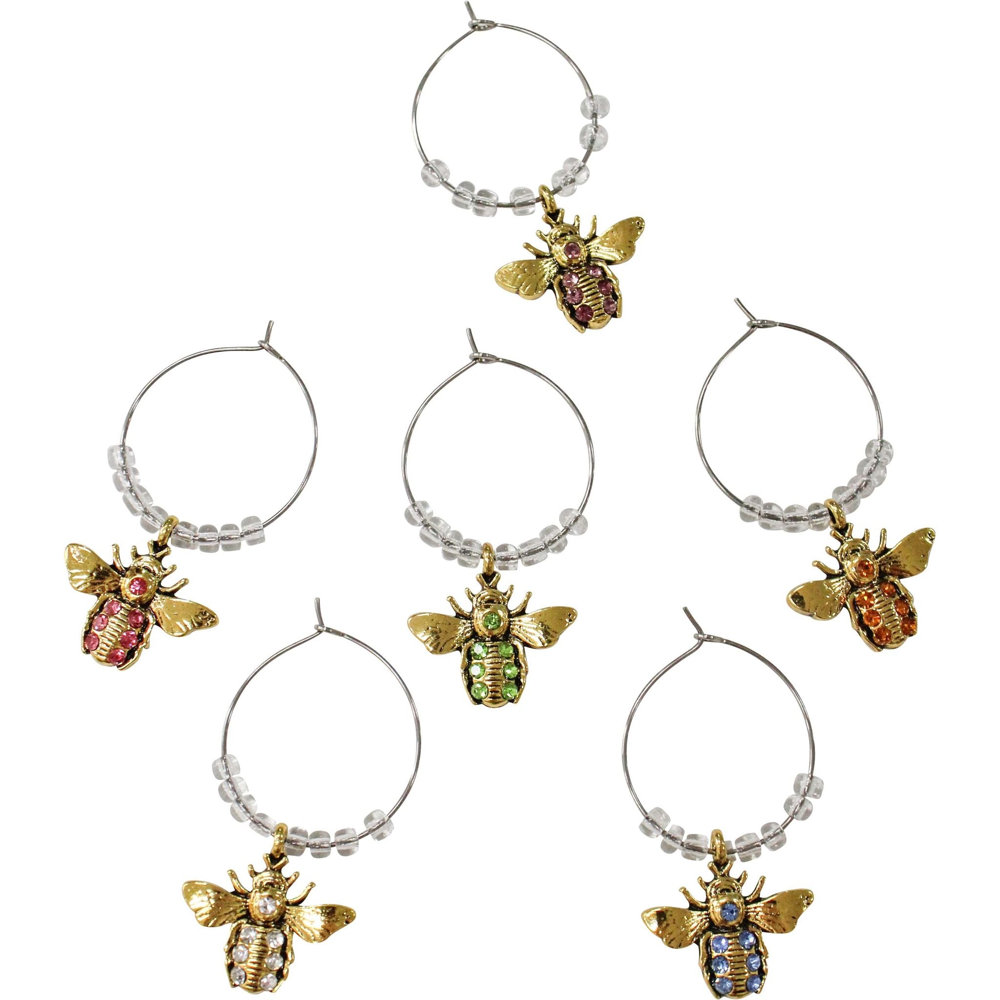 gold bee-shaped charms with coloured gems in pink, green, orange, clear, blue, and purple tones; clear round beads on silver metal wire loops; each charm is attached to a hoop for hanging on wine glasses; charms feature detailed bee design with wings and body segments;
