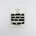 Four black elastic hair ties on retail card; Each tie decorated with round pearl-look beads; White backing card with brand name and logo; Simple, minimal packaging design;