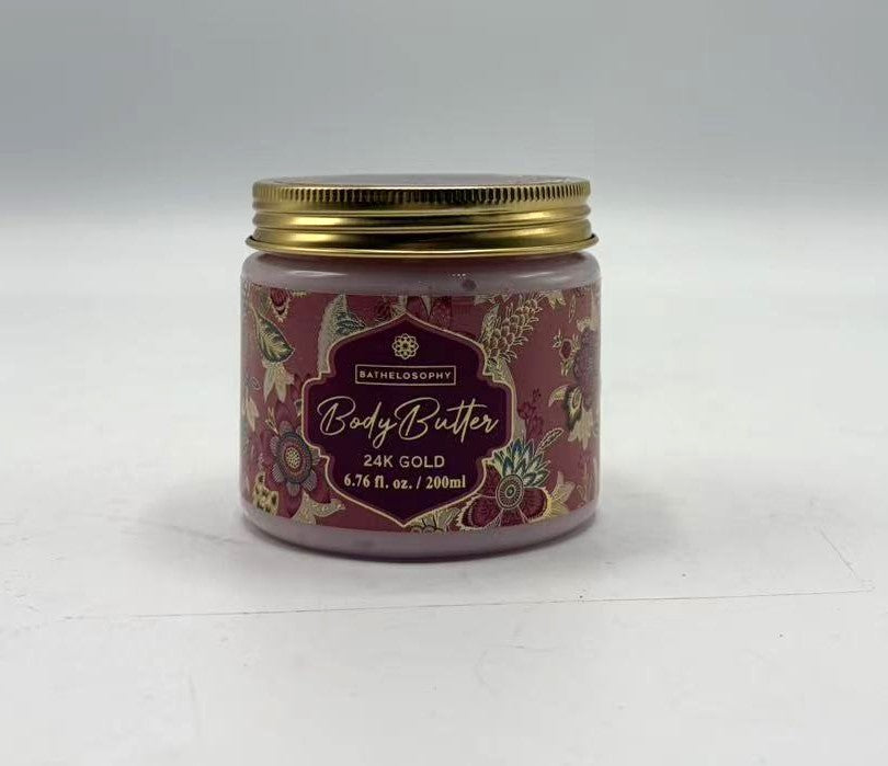 gold metal screw lid; decorative floral patterned label; pink tinted cream visible inside jar; round clear plastic jar;