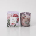 glass container with pink and white rose design; boxed packaging with matching floral pattern; light pink wax visible inside glass; compact cylindrical shape;