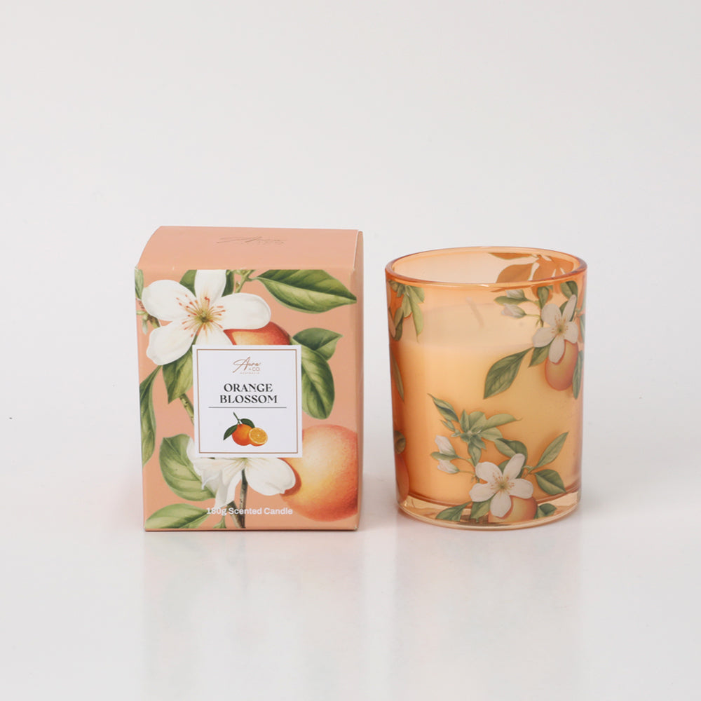 Orange blossom floral pattern on glass holder; Matching orange and green botanical design on box; Soft orange tinted glass candle holder; Boxed candle packaging; 180g weight indicated;