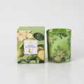 Green glass candle holder with pear and honeysuckle floral print; Matching green box with pear and flower illustrations; 180g candle weight indicated on packaging; White candle wax visible inside glass;