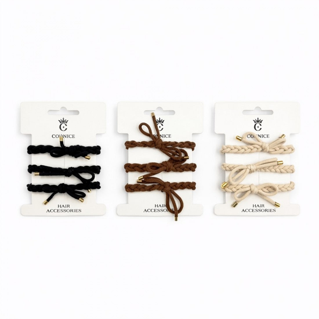Braided hair ties shown in black, brown and beige tones; Gold-coloured metal tips at the ends of each tie; Each colour set displayed on white branded backing cards; Looped and knotted designs visible on the ties;