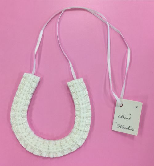 horseshoe shape; cream coloured ribbon material; attached white ribbon string; small white tag with text 'Best Wishes'; pink background;