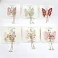 Butterfly-shaped hair clip with floral wings; Gold-tone metal body and clip; Dangling gold chains with pearl-like beads; Assorted soft pastel and bright colours shown on cards;