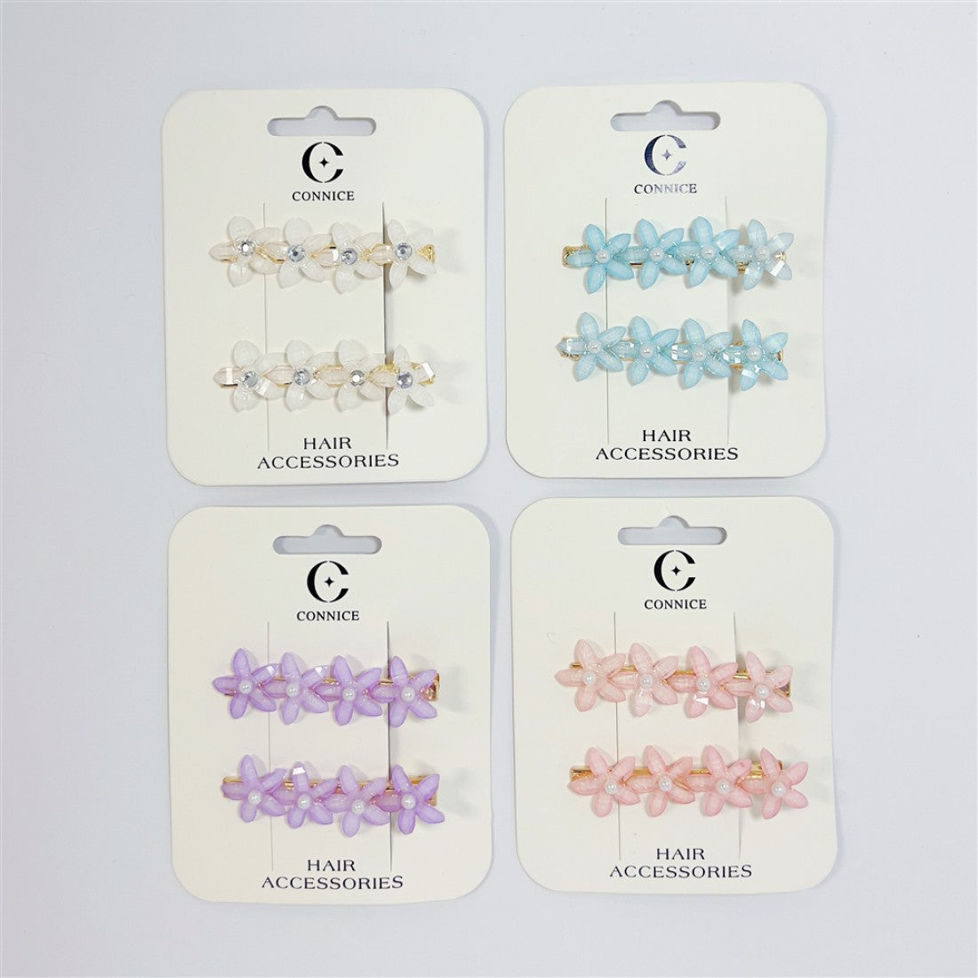 Hair clips with flower-shaped decorations; Pastel colours including white, blue, purple and pink shown; Mounted on CONNICE branded hair accessories cards; Each card holds a pair of matching clips;