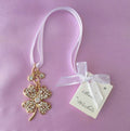 gold-tone four-leaf clover shape; clear diamante stones embedded; white sheer ribbon attached; white tag with 'Best Wishes' text and small bow;