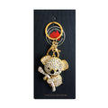 gold-tone koala shape keyring; covered in clear diamond-like stones; koala holding a branch; attached to gold split ring and clip; packaged on black branded card;