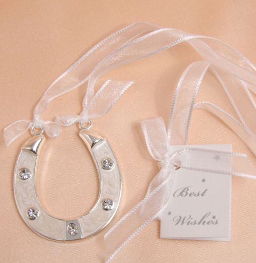 white enamel horseshoe shape; five embedded clear crystals; attached sheer white ribbon; small Best Wishes tag; silver-tone metal edges;