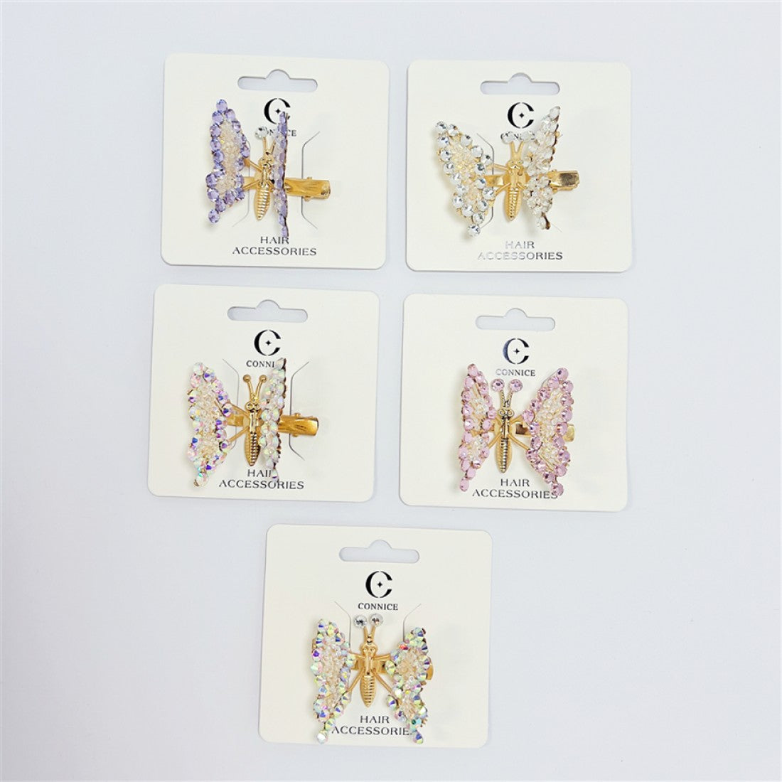Butterfly-shaped hair clips with diamanté-style stones; Gold-tone metal clip and butterfly body; Assorted pastel colours including lilac, pink and white; Each clip presented on branded backing card;