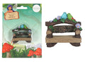 Small bench with wood texture; Two colourful birds (blue and green) on top; Floral decorations in purple and green; Sign with text 'Fairies Welcome';