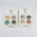 Set of four small flower-shaped claw clips; Iridescent, gradient plastic in assorted pastel tones; Mounted on white branded backing card; Frangipani-style five-petal design;