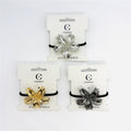 Elastic black hair band; Metal frangipani-shaped flower buckle; Metallic finishes including silver, gold and dark silver; Each piece displayed on white branded backing card;