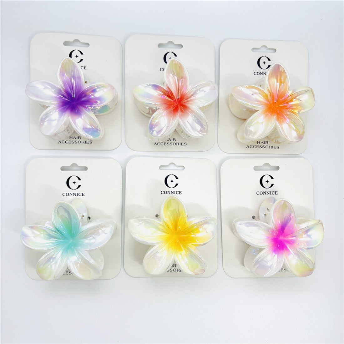 Flower-shaped frangipani hair clips; Iridescent pearly AB finish; Central gradient colours such as purple, red, yellow, blue and pink; Mounted on white branded backing cards; Approximate 8cm wide claw clip size;