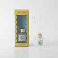 clear glass diffuser bottle; gold-coloured bottle cap; yellow box packaging with window; white diffuser reeds; label with lemons and striped background;