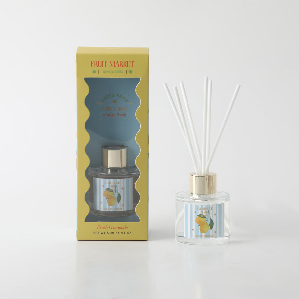 clear glass diffuser bottle; gold-coloured bottle cap; yellow box packaging with window; white diffuser reeds; label with lemons and striped background;