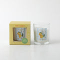 Yellow packaging box with window showing candle; Clear glass container with candle inside; Label on candle with lemons and blue stripes; Green sticker on box indicating 'Fresh lemonade' scent;