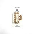 Gold-tone rectangular claw clip; Decorated with small white flower embellishments; Mounted on branded backing card; Spring hinge and interlocking teeth design;