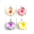 Flower-shaped hair claw clip; Iridescent holographic finish; Soft gradient colours including pinks, yellows and purples; Packaged on white backing card branded “Connice”;