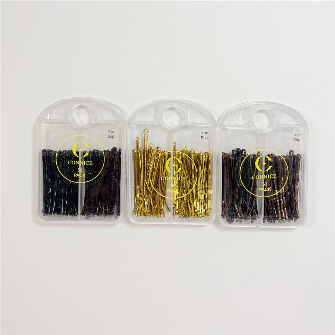 Hair pins shown in black, gold and brown tones; Pins stored in clear plastic cases; Packaging printed with brand name and 50 pack text; Cases have a round hole at top for hanging or carrying;