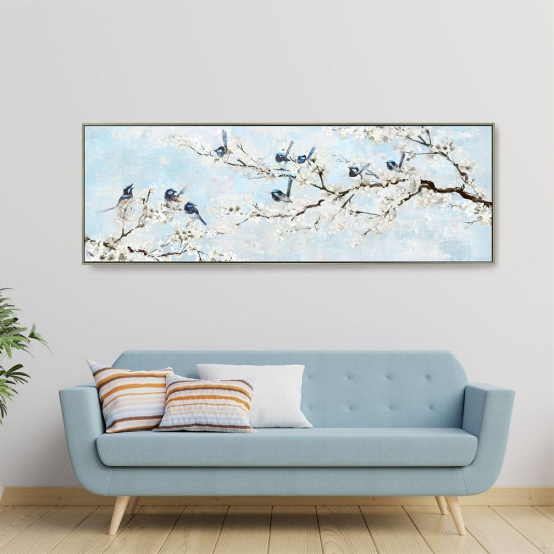 Large rectangular canvas print; Soft blue and white colour scheme; Depiction of blue birds on flowering branches; Slim wooden frame surrounding canvas; Printed artwork with hand painted style;