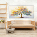 Colourful tree design with yellow, blue, orange and purple leaves; Large rectangular canvas shape; Slim black frame around the artwork; Textured brushstroke painting style; Canvas mounted on stretcher bars;